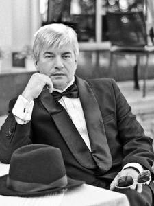 一个灰色头发的老流氓穿着黑色西装坐在夏日咖啡馆 inretro 风格照片