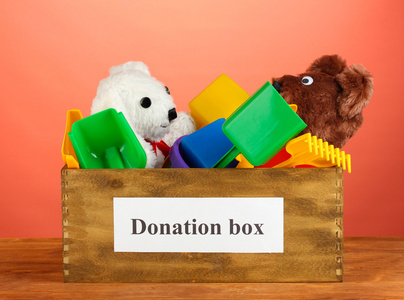 捐款箱与儿童玩具上红色背景特写