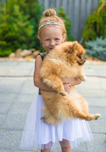 与她的宠物狗在户外的公园中的金发小姑娘