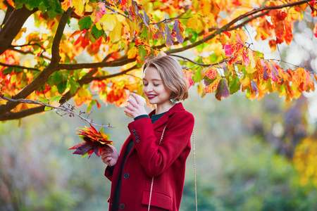 美丽的年轻妇女与束五颜六色的秋天叶子在公园散步在秋天天和喝咖啡去