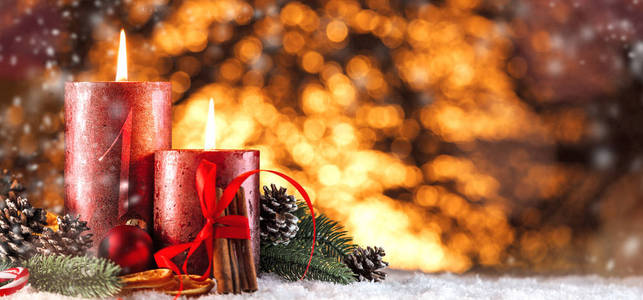 在雪地和木质背景下燃烧蜡烛和圣诞装饰