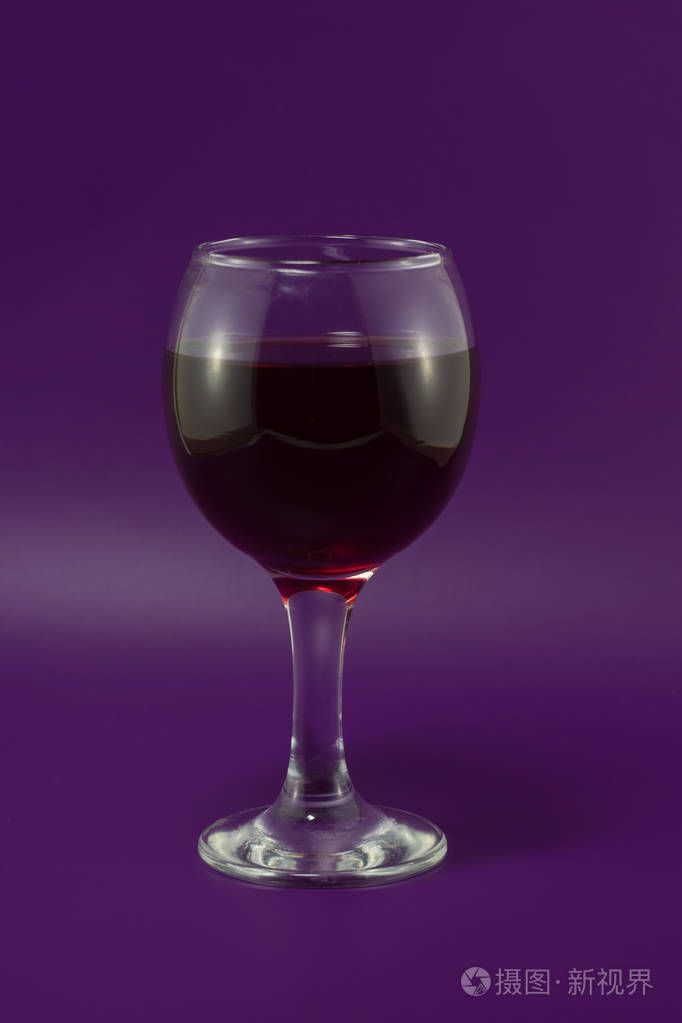 紫罗兰色背景下的一杯红葡萄酒