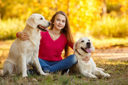 在秋天的狗年轻的女孩坐在她的狗猎犬在秋天的场景中与地面上的肖像