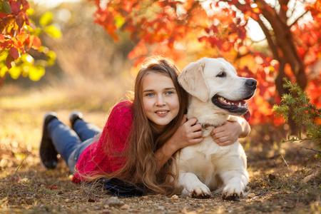 年轻的女孩坐在她的狗猎犬在秋天的场景中与地面上的肖像