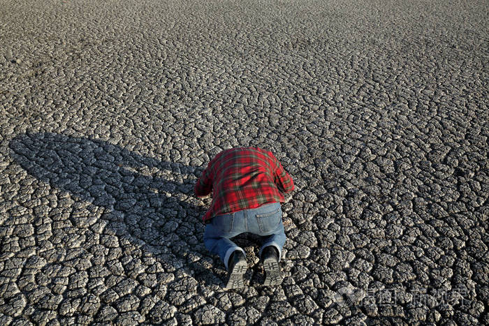 绝望的人跪了下来, 祈祷在干旱, 自然灾害后干燥破碎的土地