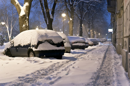 被雪覆盖的汽车机器清除城市街道上的积雪冬季城市景观.