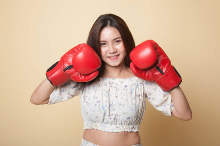 年轻的亚洲妇女与红色拳击手套米色背景