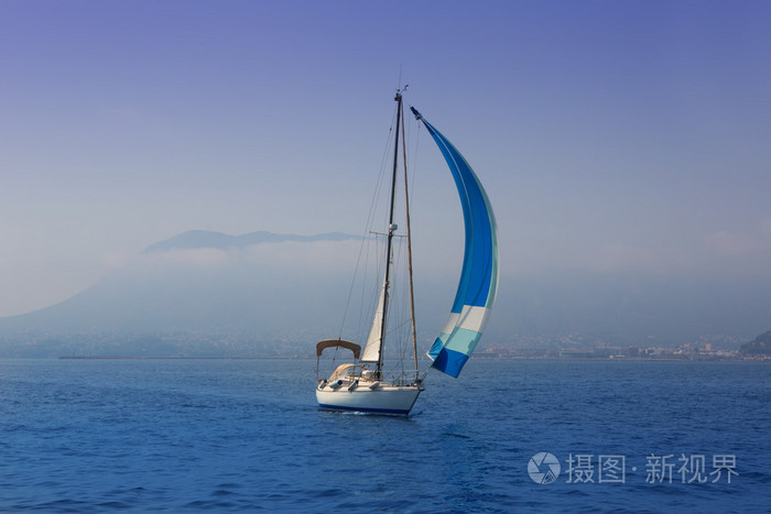 蓝色的大海与在有雾的海岸航行的帆船