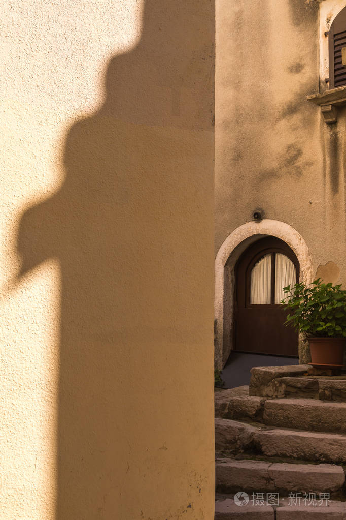 房子的门面与另一个房子的屋顶的影子下半年创建的院子与石楼梯植物在