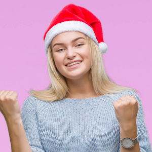 年轻的白种女人戴着圣诞帽子在孤立的背景下非常高兴和兴奋做赢家手势举起双臂, 微笑和尖叫的成功。庆典理念