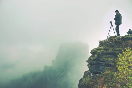 自然摄影师创造艺术在风景点在山。男子看着他的大相机取景器, 拍照的无聊惊人的一天
