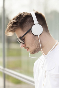 英俊的年轻人喜欢在户外听音乐。选择性对焦和小景深