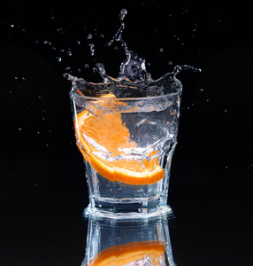 柠檬在水溅片柠檬溅入一杯水,用一种喷雾的水滴悬浮在一个黑色的背景