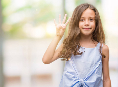 黑发西班牙裔女孩显示和指向手指数四, 而微笑着自信和快乐