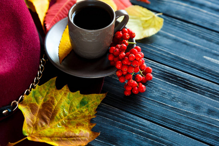 帽子勃艮第或马尔萨拉颜色在灰色木质背景与秋天红色, 黄色叶子和杯子咖啡或茶。时尚潮流秋冬舒适舒适理念