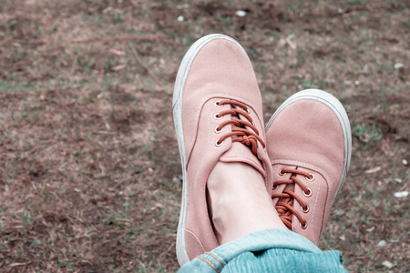 女性的脚在粉红色的运动鞋在草背景, 复古风格