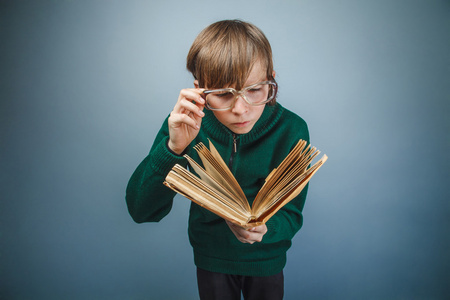 欧洲人的小男孩在眼镜上读一本书的十年