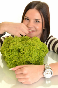 快乐的年轻女人举行绿色生菜和微笑，在白色背景