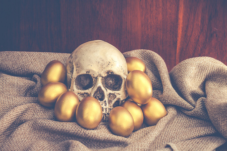 人类的头颅骨上棕色袋复活节金蛋被包围