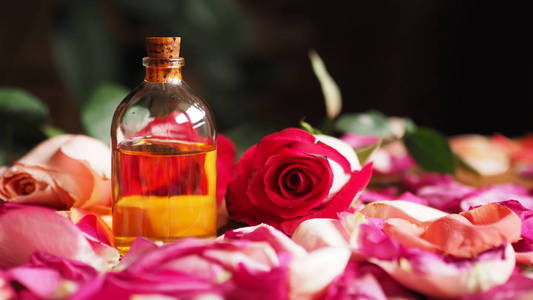 芳香油玻璃瓶之间的玫瑰花瓣在桌子上, 天然原料, 选择焦点