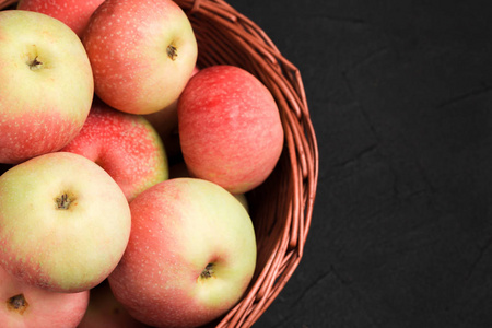 苹果拷贝成熟的原始苹果在柳条篮子在黑色背景与拷贝空间-水平横幅与