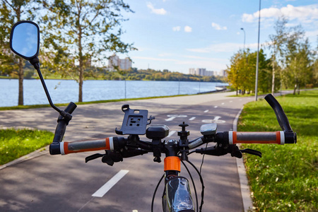 从骑自行车的一侧观看。一个残酷的自行车舵在自行车路径的背景下沿着河的路堤的角度