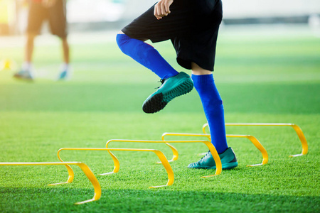 少年足球运动员慢跑和跳跃在标记和黄色障碍之间。足球训练