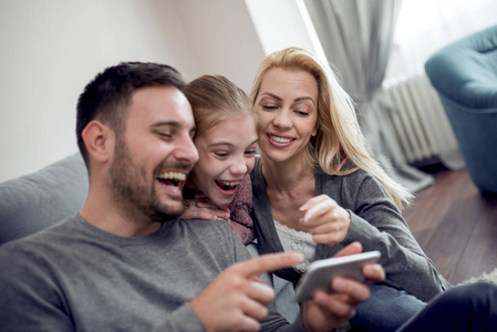 假日, 技术和人概念快乐的家庭坐在沙发上, 并采取自拍图片与智能手机在家里