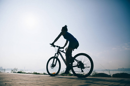 骑自行车的妇女骑山麦克在日出海滨