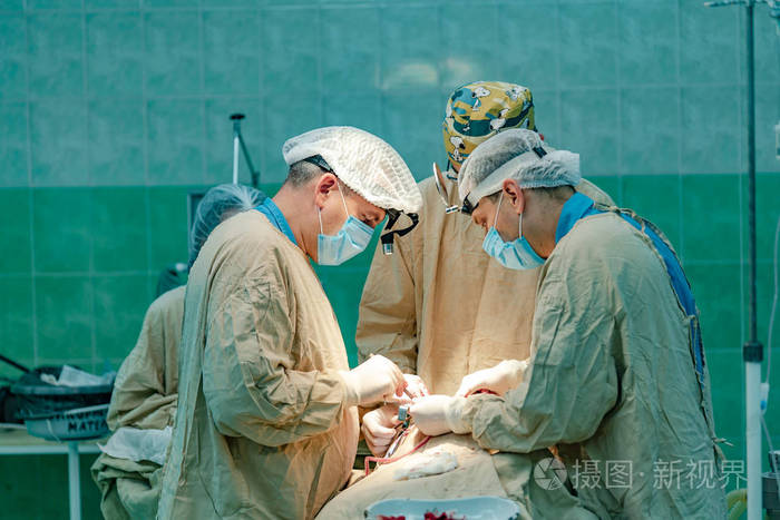 三名医生在医院手术室的护士参与下进行病人手术.特写