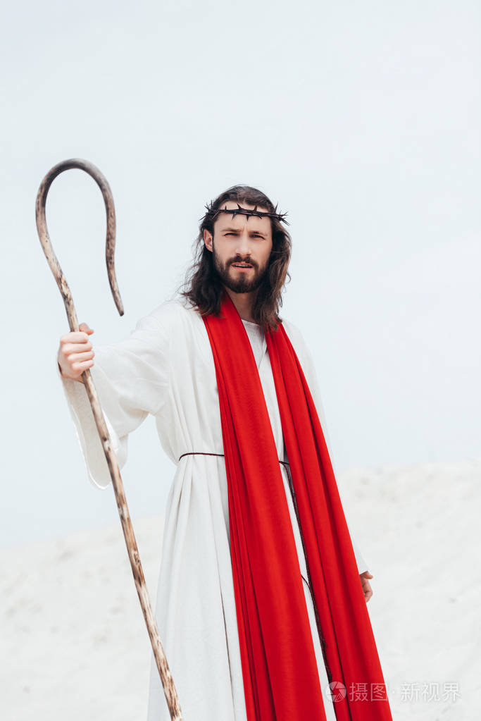 长头发的耶稣在沙漠中站立与木职员