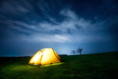 山中的帐篷星光灿烂的天空下, 夜晚群山中闪耀的露营帐篷照片