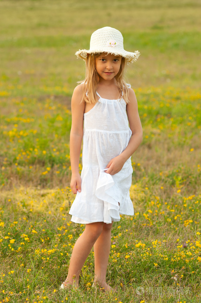 可爱的小女孩站在草地上在阳光灿烂的夏天一天