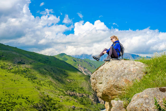 一个背着背包的女孩坐在一块石头上.山风景.在高加索爬山