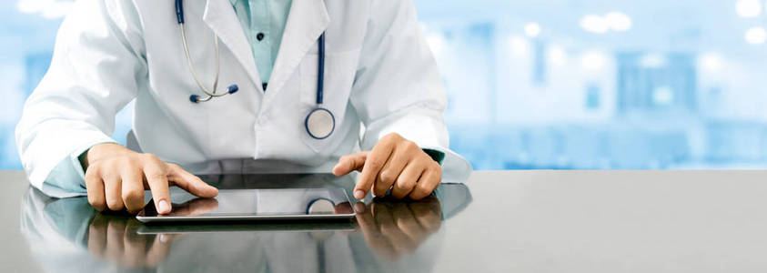 男医生坐在餐桌旁, 用平板电脑在医院办公室。医疗保健人员和医生服务