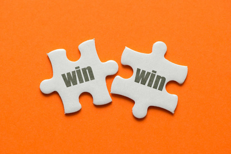 双赢拼图概念在橙色背景上的两个匹配的谜题赢得胜利照片