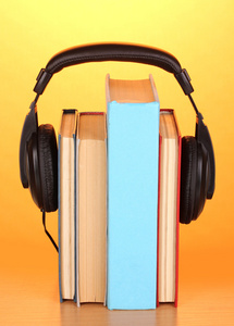 耳机上橙色背景上的木桌子上的书
