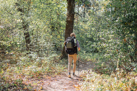 年轻人独自享受徒步旅行与北欧行走棍子在森林