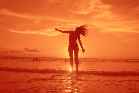 快乐的年轻女子在海滩上玩, 自由的概念和暑假的乐趣和跳跃