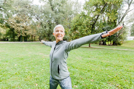 健康中年妇女在运动服做伸展运动在公园