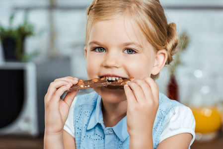 可爱的孩子吃可口的巧克力和微笑在照相机