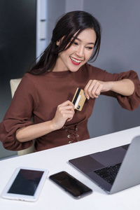 愉快的妇女使用笔记本电脑在线购物与信用卡