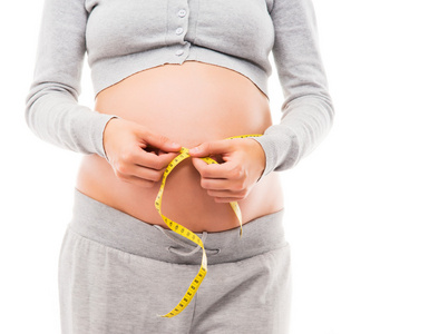 一名怀孕的妇女，测量她的肚子，用胶带