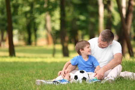 快乐的父亲与儿子休息在格子在绿色公园