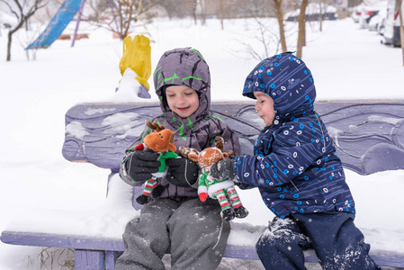 两个可爱的学龄前儿童兄弟男孩在冬天穿在雪和玩具驯鹿玩