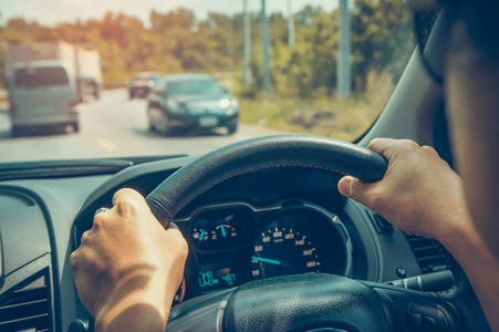 人类手牵方向盘紧.他在森林路开汽车.夏日阳光明媚的户外活动.
