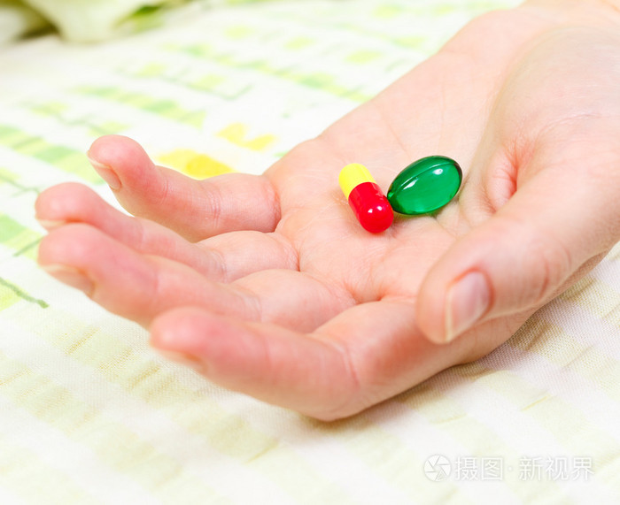 她手里握着两片药的女人手的特写