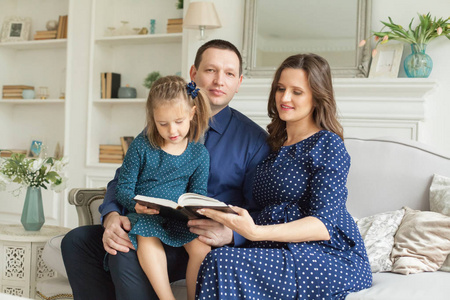 幸福的家庭。母亲父亲和女儿一起在家看书