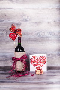 红葡萄酒瓶和用红心装饰的可乐瓶和可乐在木桌上。情人节庆祝概念。复制空间