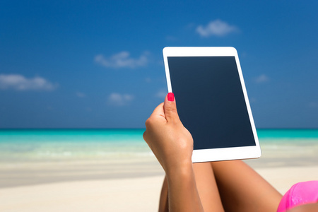 在海滩上的妇女手中的空白空平板电脑